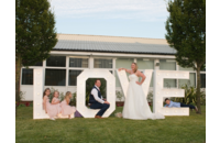 wedding couple and bridesmaids posing in white LOVE letters sign