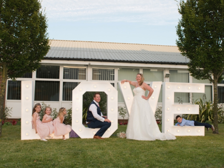 wedding couple and bridesmaids posing in white LOVE letters sign